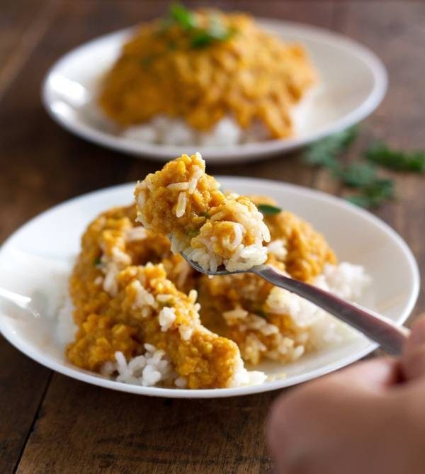 Red lentil dhal with rice on a white plate.