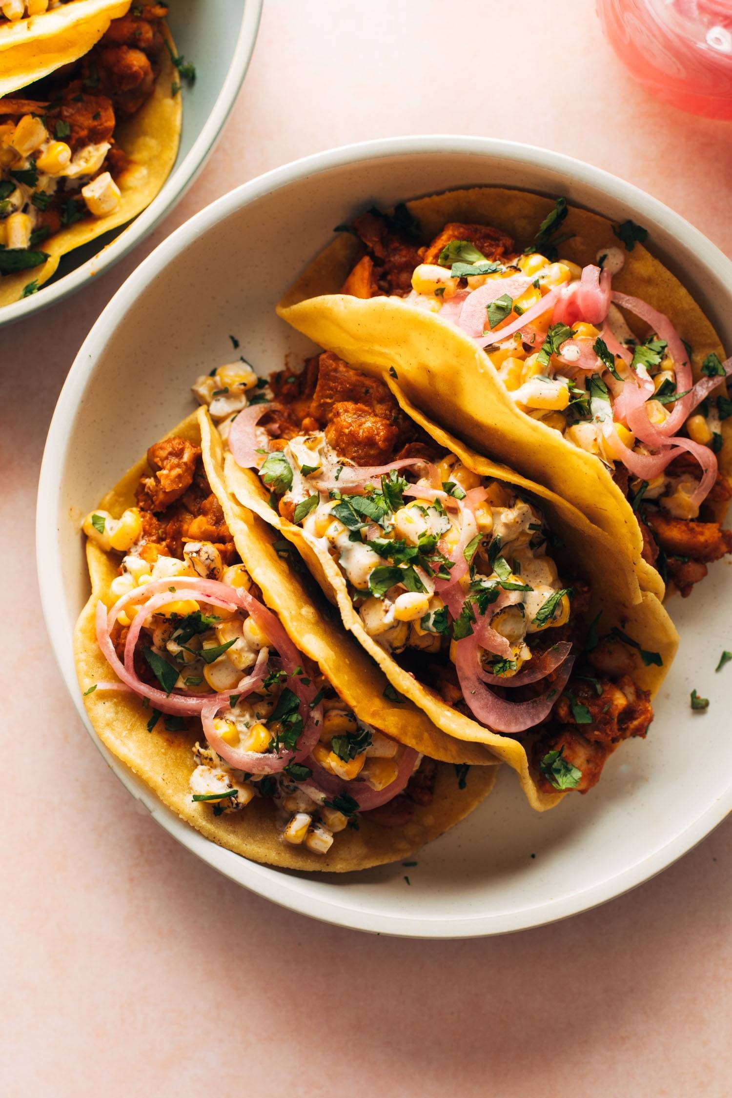 Red chile chicken tacos topped with creamy corn.