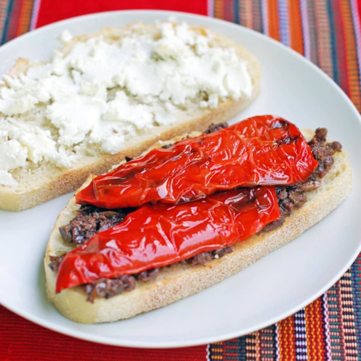 Red pepper and goat cheese panini in half on a white plate. 