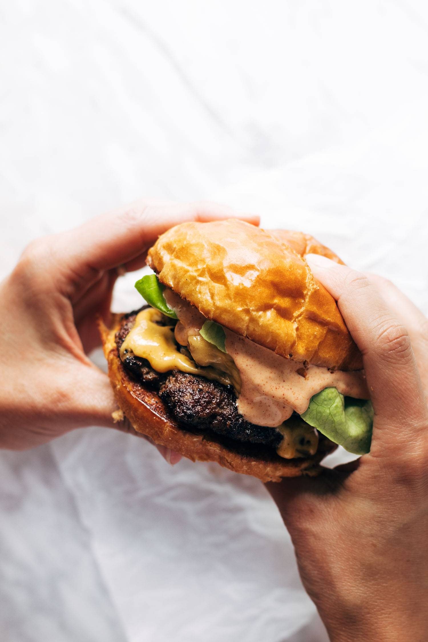 Two hands holding a smash burger.
