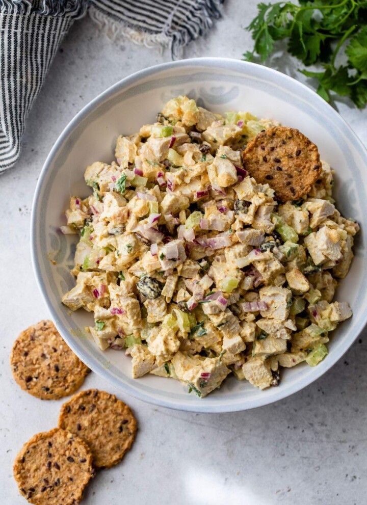 Curry chicken salad in a white bowl with crackers.