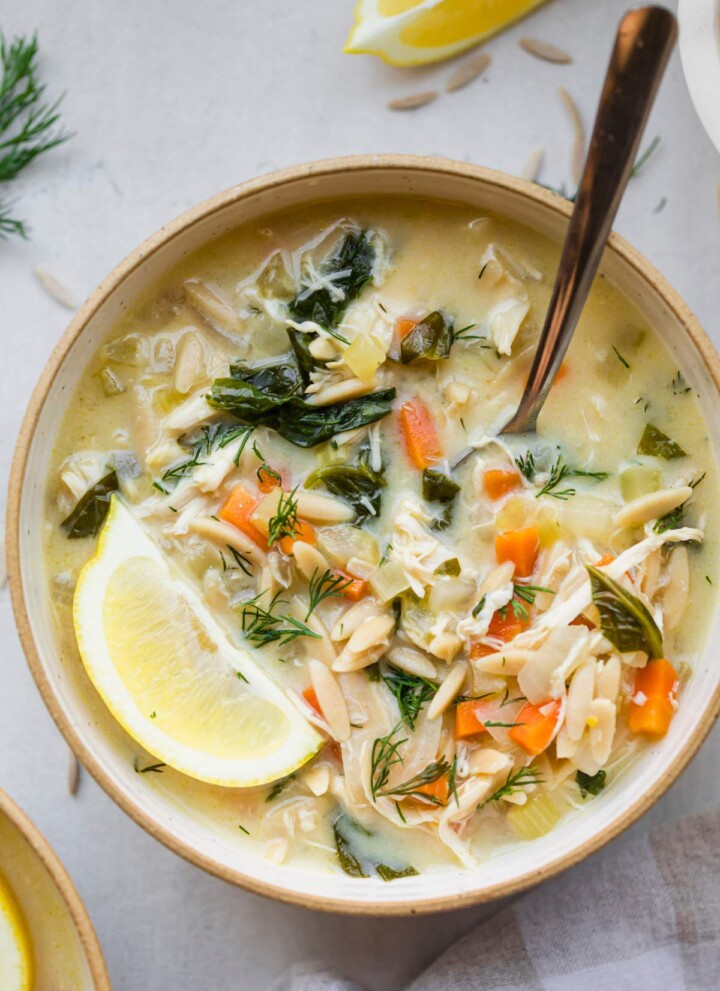 Bowl of lemon chicken soup with a lemon wedge on top.