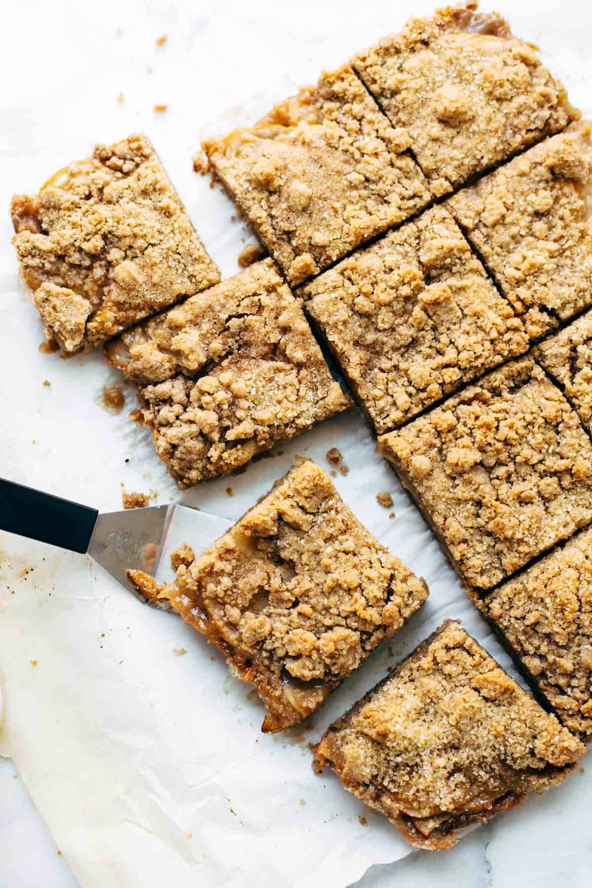 Caramel Apple Crisp Bars on parchment paper with a spatula