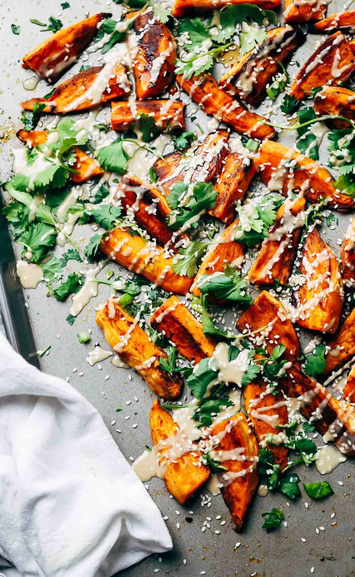 Sesame Roasted Sweet Potatoes topped with tahini, sesame oil, cilantro, and sesame seeds.