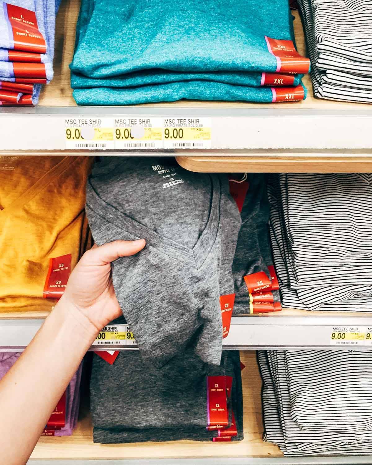 Hand holding a grey shirt.