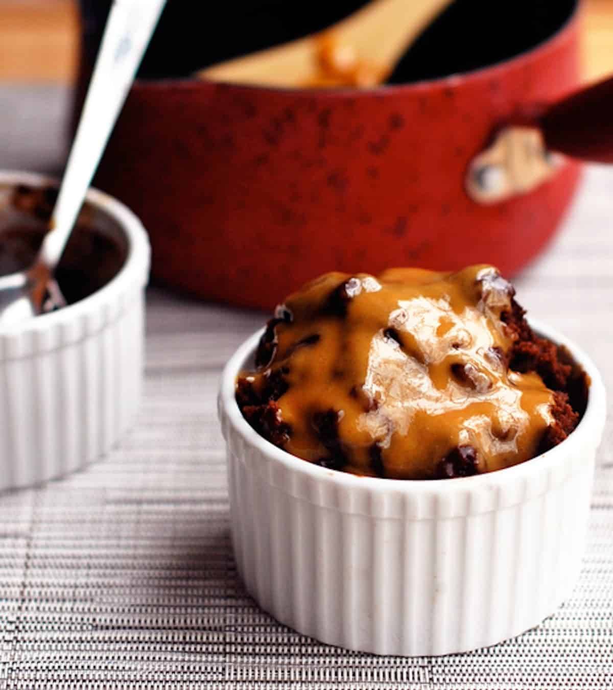 Hot fudge cake covered with homemade peanut butter sauce in a white dish.