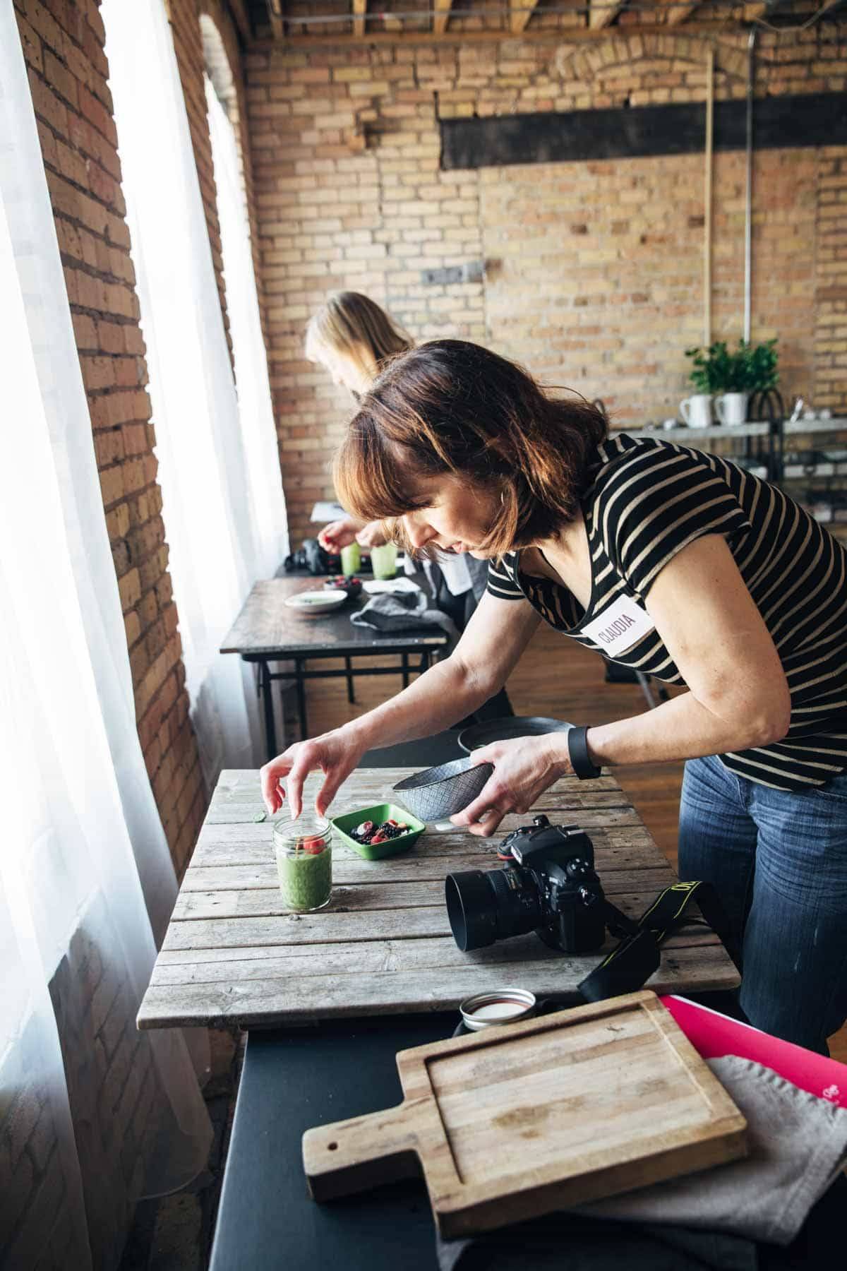 Woman styling food in a jar to photograph.